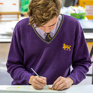 A Senior male student painting a canvas