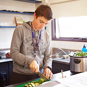 Student chopping up a cucumber