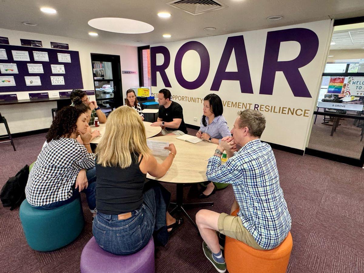 Teachers participating in professional learning with a ROAR sign in background